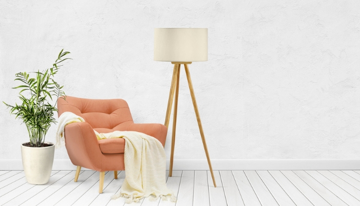 A peach armchair with a white blanket sits in front of a white wall.