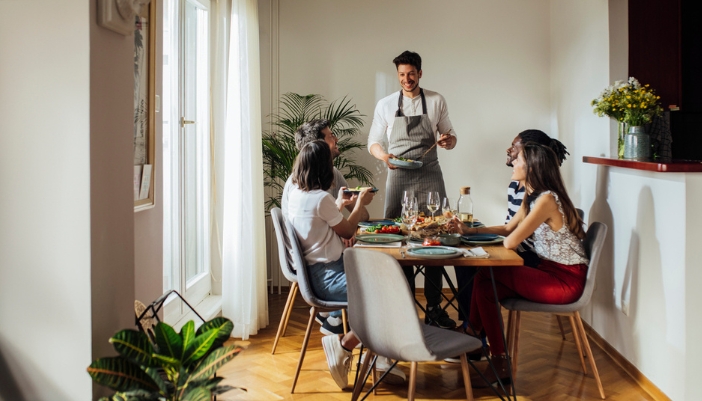 A group of friends shares a meal at home in a modern dining room.