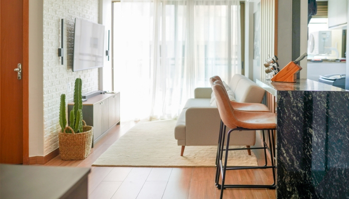 A compact living room with a flat screen TV and a neutral couch.