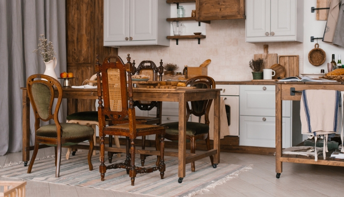 A dark wooden table in a kitchen with mismatched vintage chairs.