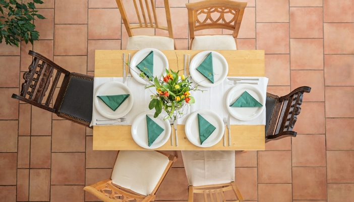 A birds eye view of a natural wooden table with mix-match chairs.