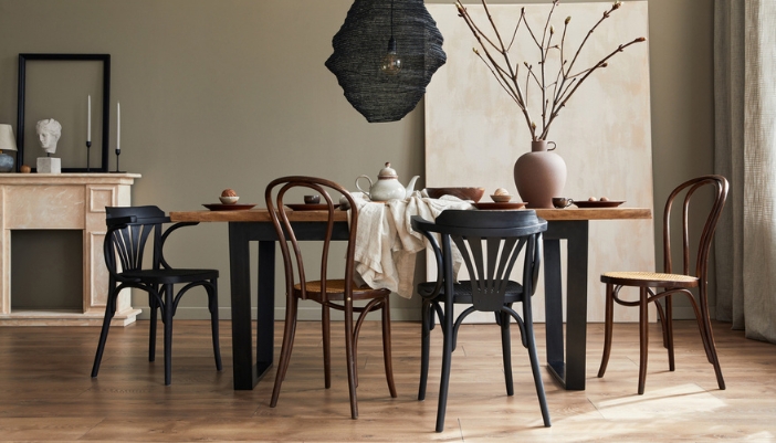 A dining table with mismatched black metal and dark wooden chairs.