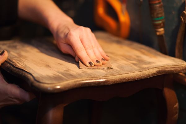 A person sanding a wooden furniture piece 
