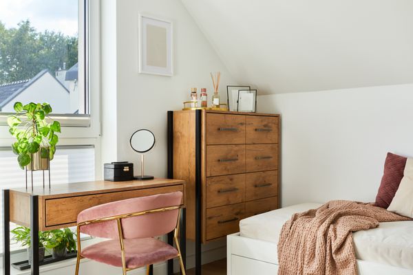 An apartment bedroom with a bed, desk, and chest 