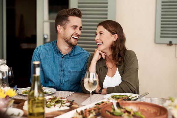 A man and a woman laughing at a dinner table 