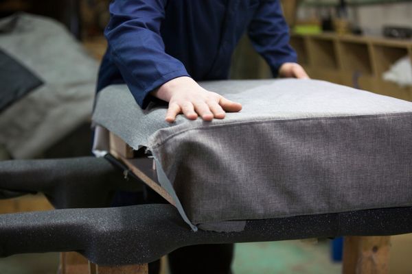 A tailor fitting a sofa with upholstery 