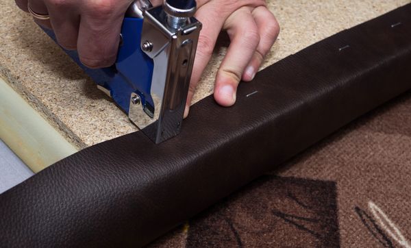 A person stabling leather upholstery to furniture 