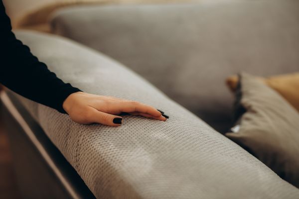 A woman running her hand across a microfiber sofa 