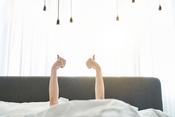 A person giving two thumbs up in bed 