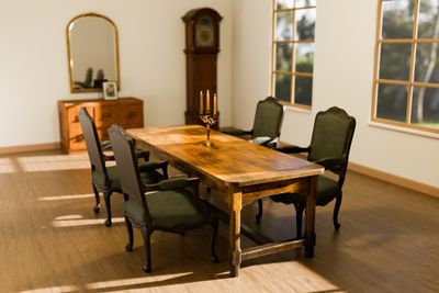 A Victorian-style dining room with a table, chairs, and storage 
