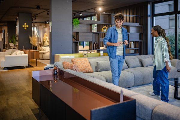 A smiling man and a woman reviewing a sectional sofa in a store 
