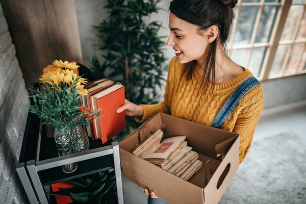 A young woman smiling while organizing books and décor 