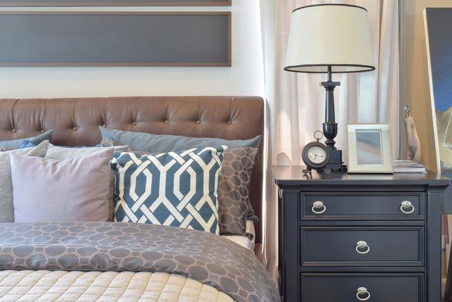 close view of a bed and a dresser next to each other with a matching navy blue and beige color scheme