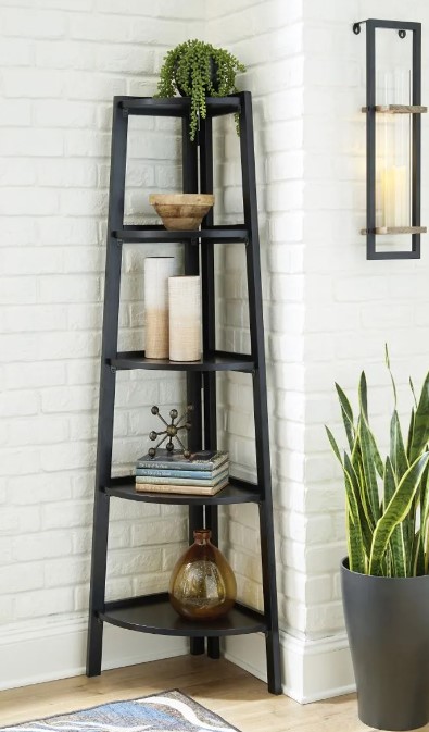A black corner bookcase with various pieces of decor