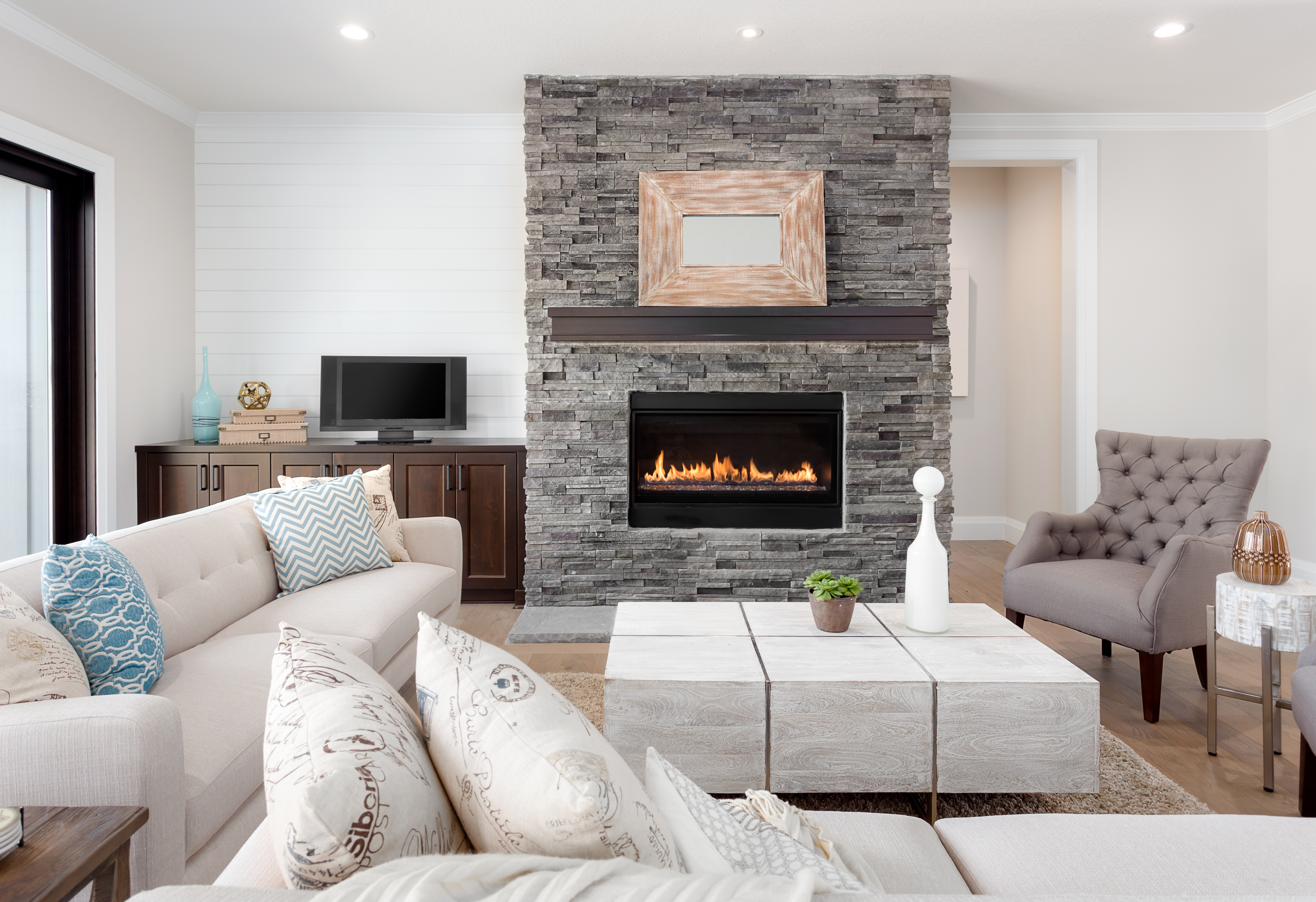 A white-theme living room with a stone fireplace 