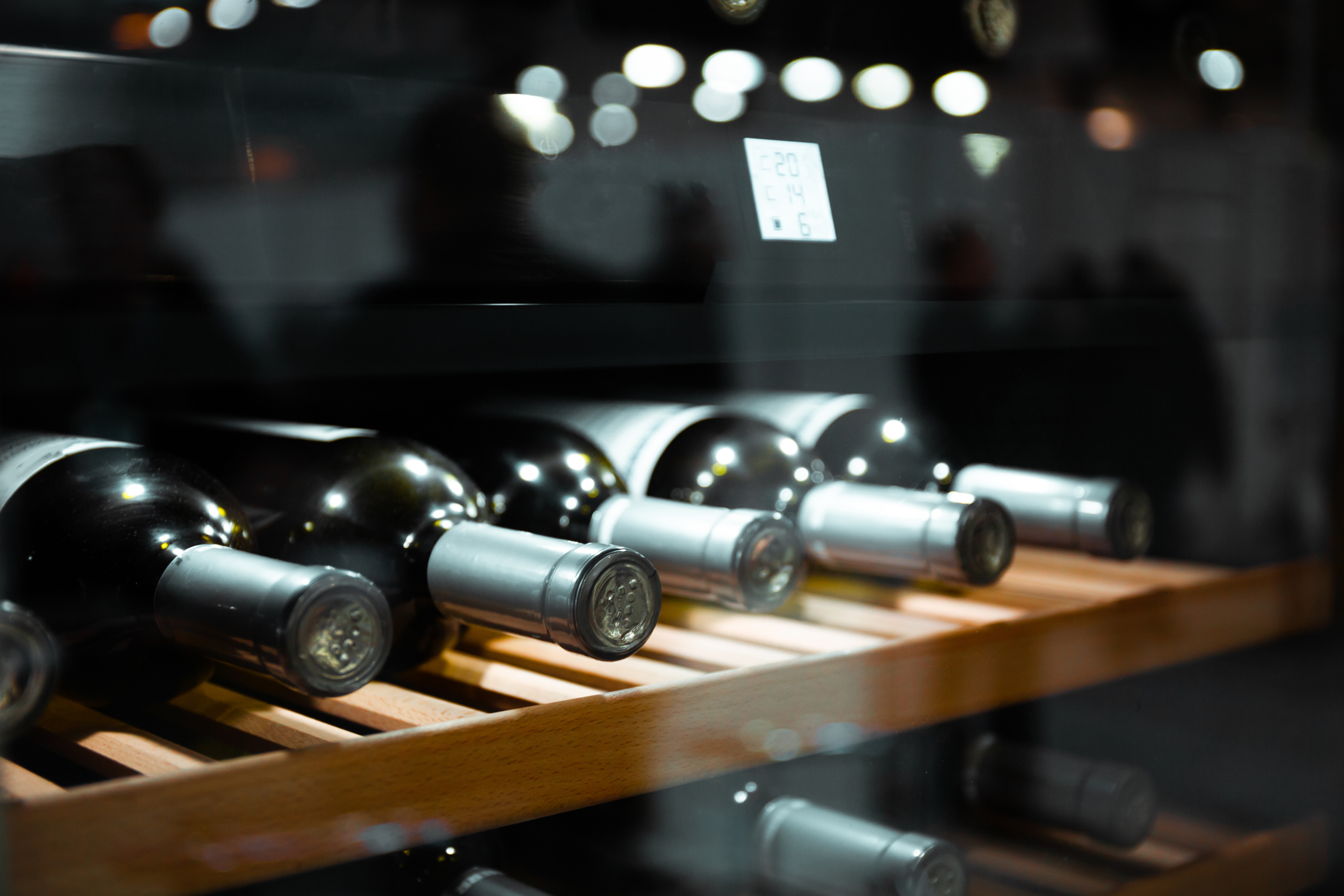 Wine bottles shown on a wooden rack inside a wine cooler 