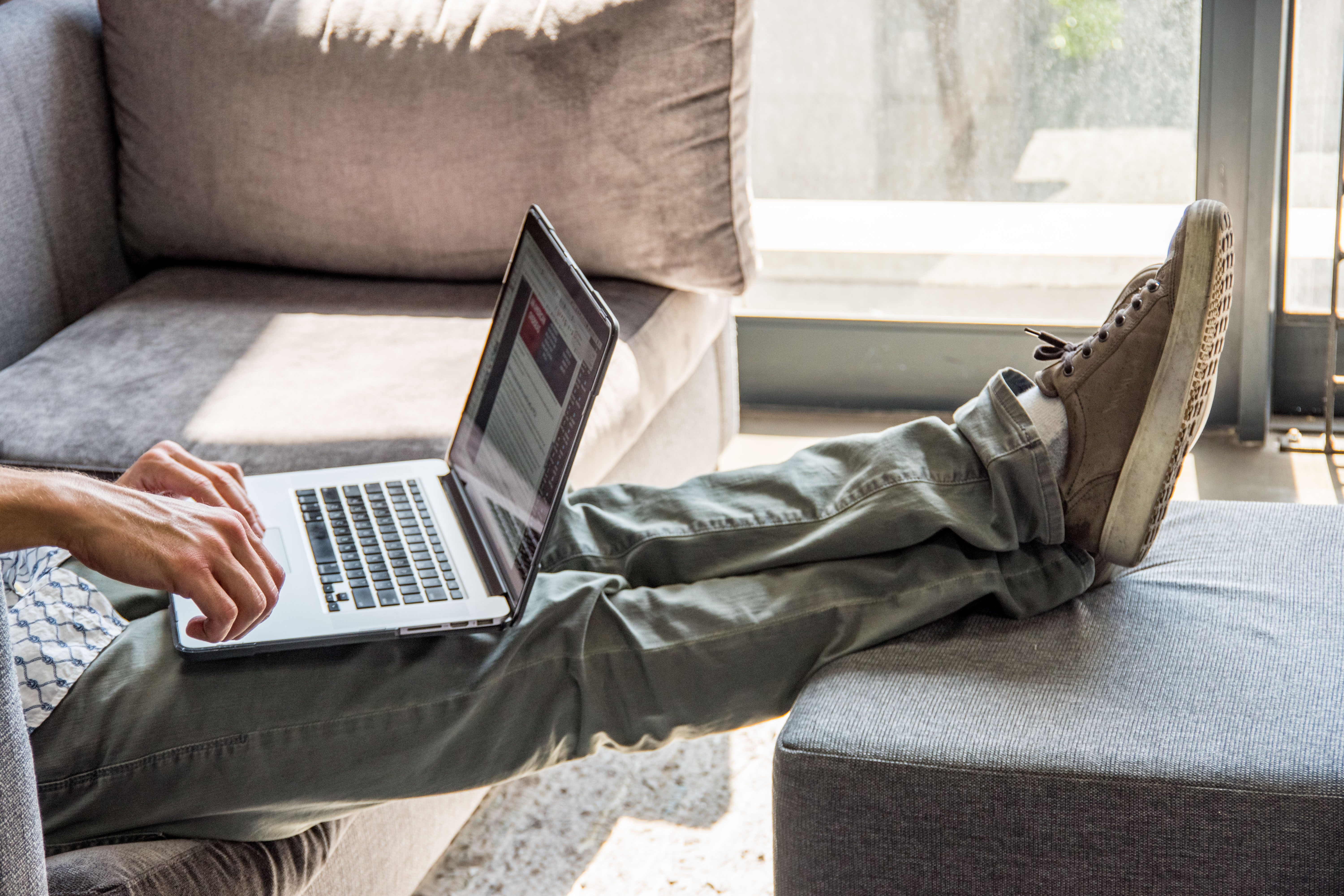 A man on a laptop with his feet on an ottoman 