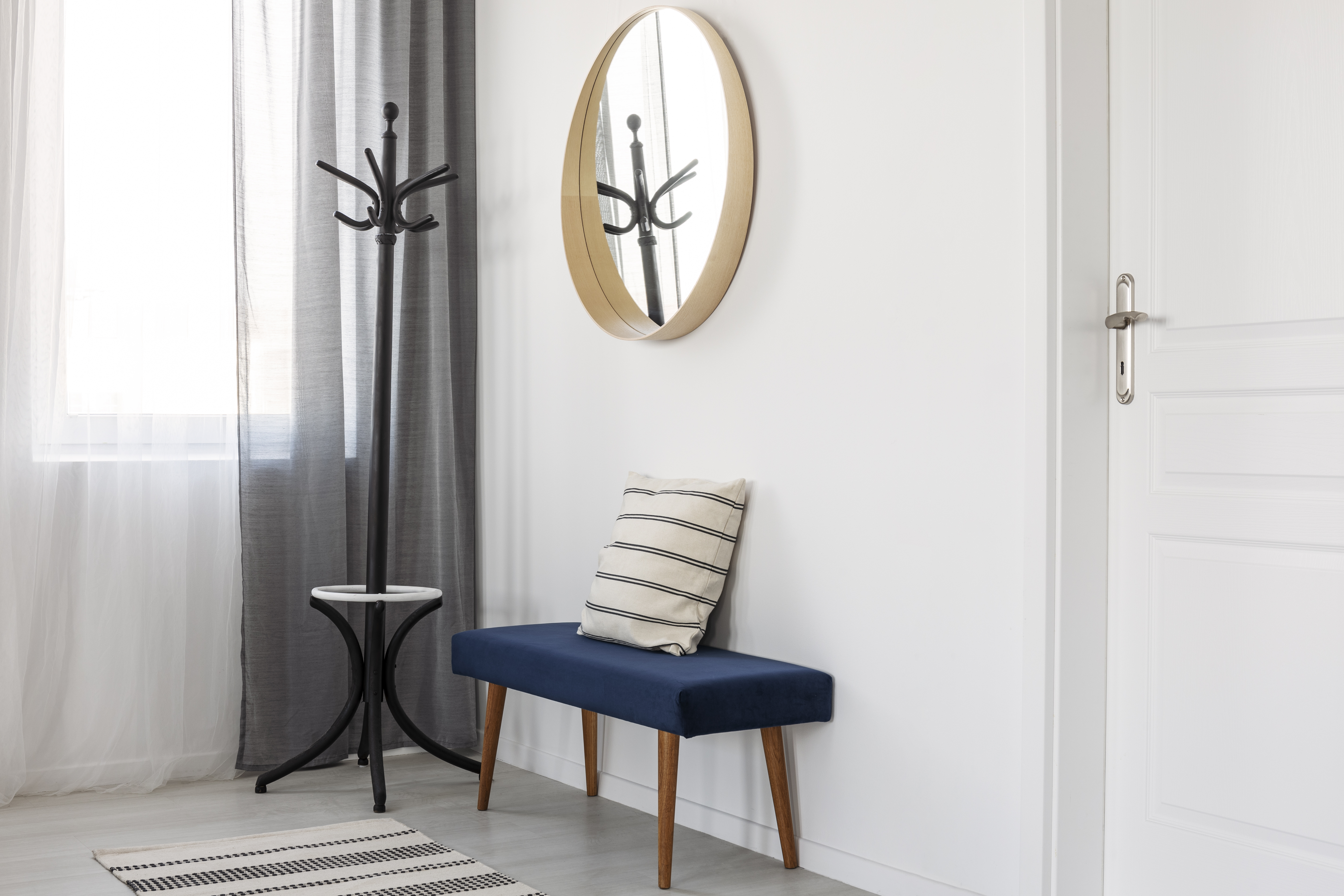 A round wall mirror above a blue bench 