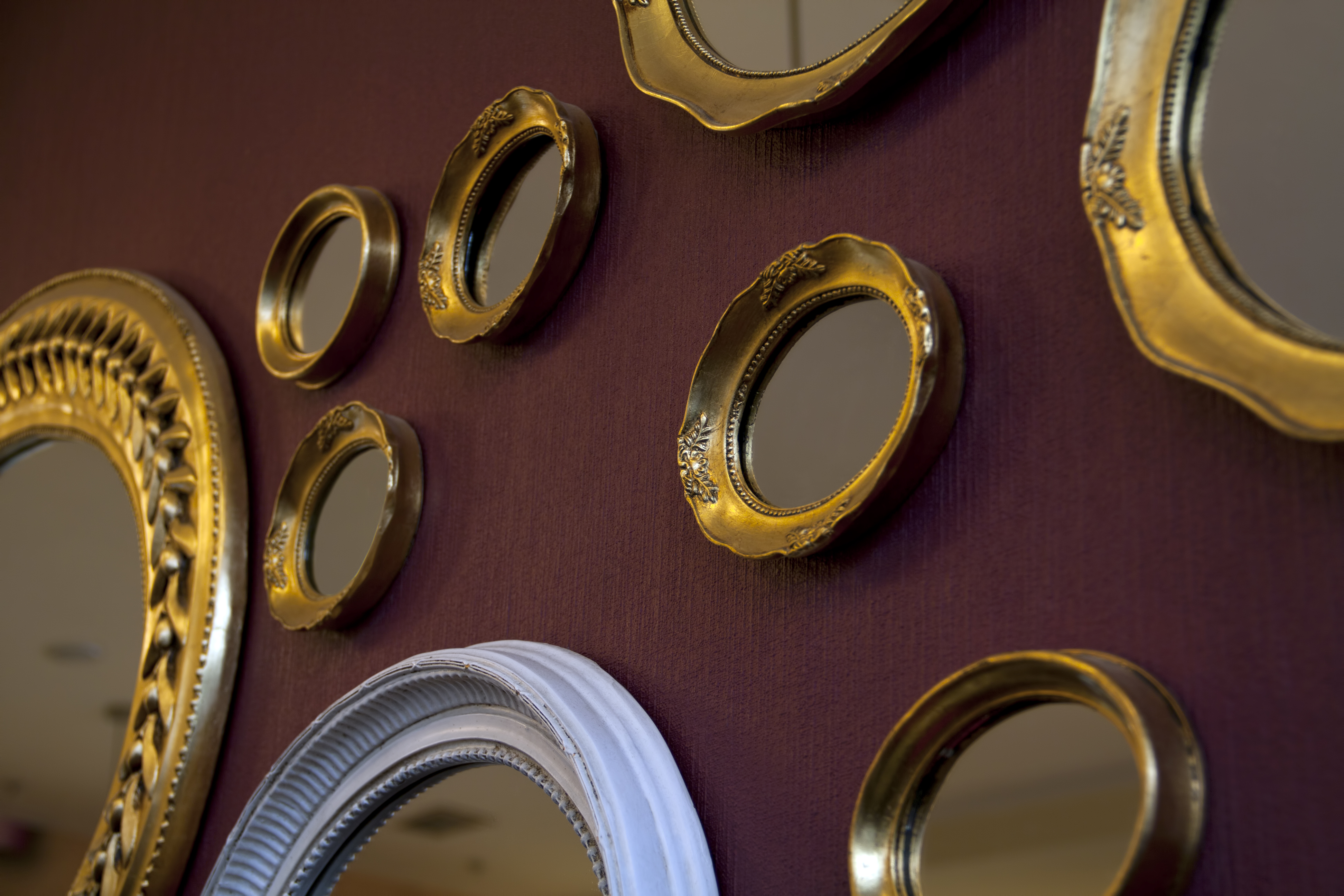 Gold round mirrors in various sizes against a garnet wall 
