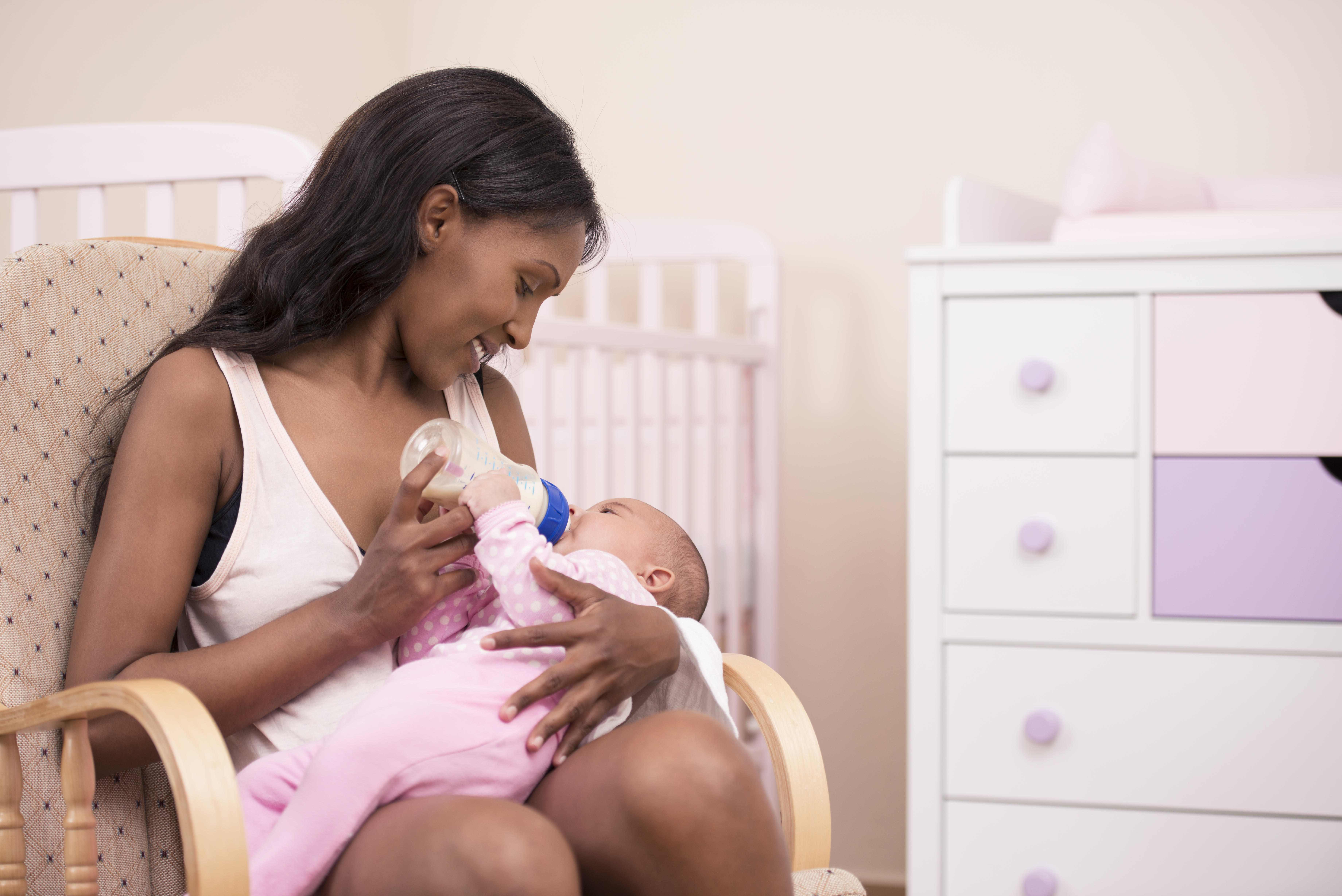 A woman feeding a baby while sitting on a rocker recliner 