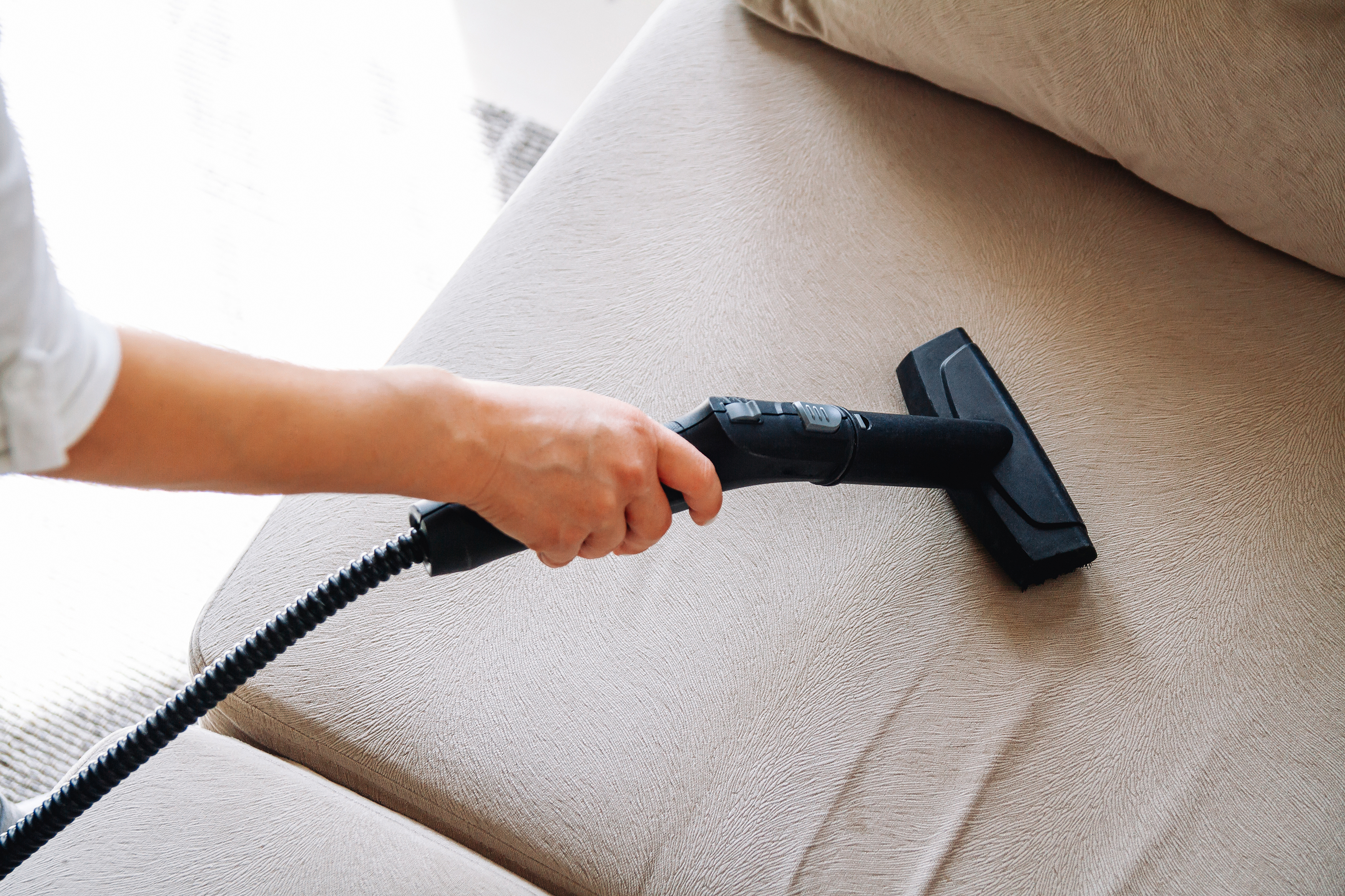 Woman using a steam cleaner to clean a sofa 