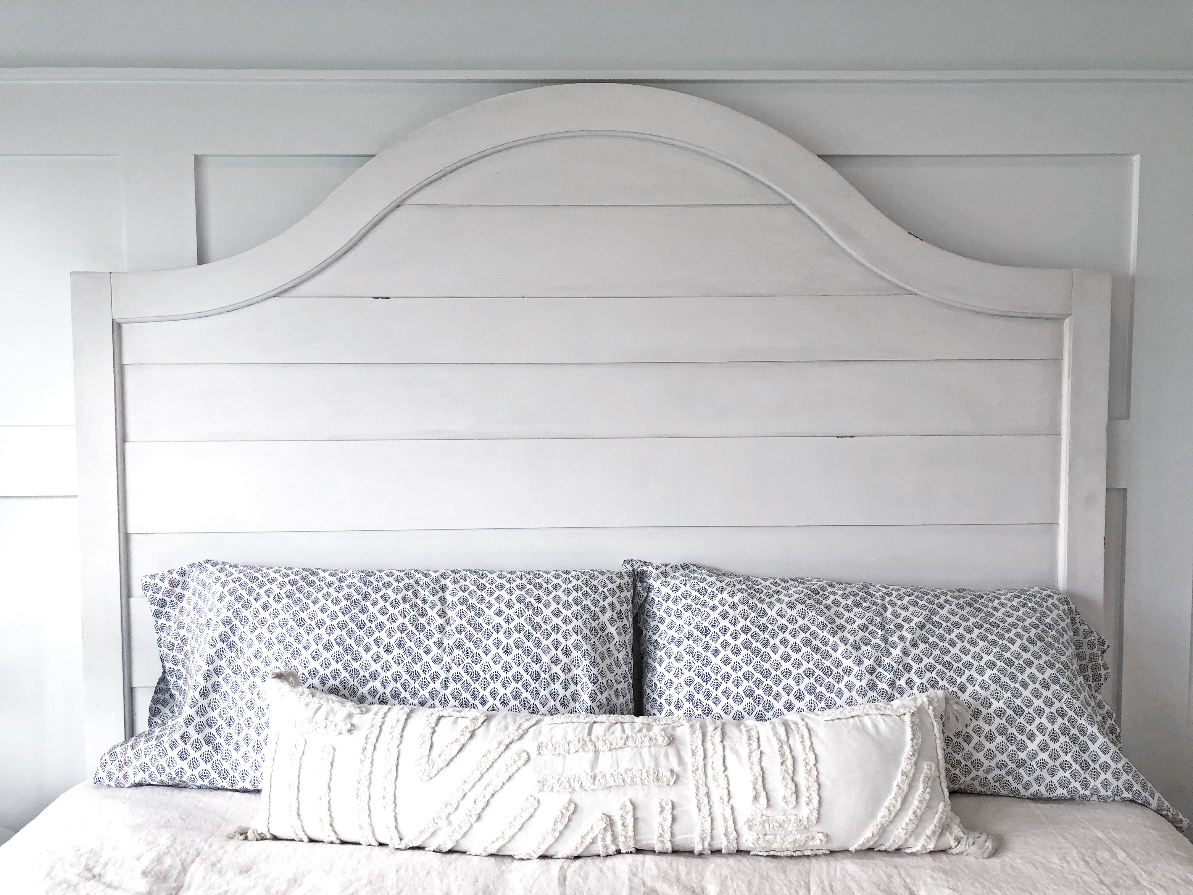 A white camel back headboard with matching decorative colors in coastal shades 