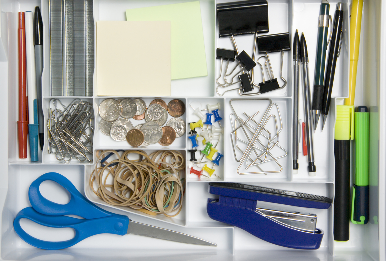 closeup of desk drawer with desk organizer tray filled with office supplies