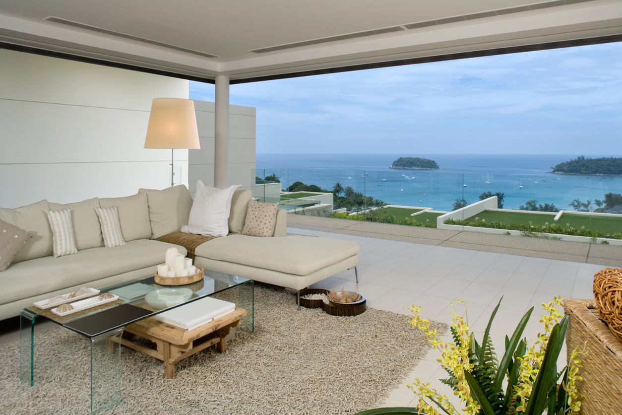 Coastal room with sectional, glass coffee table, and ocean views