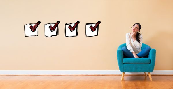 A woman smirking while in a chair next to a graphic with four red check marks in white boxes