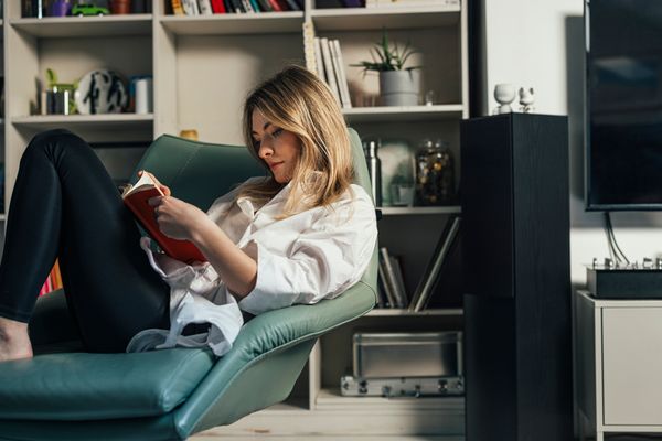 A woman seated on a leather chair reading a book