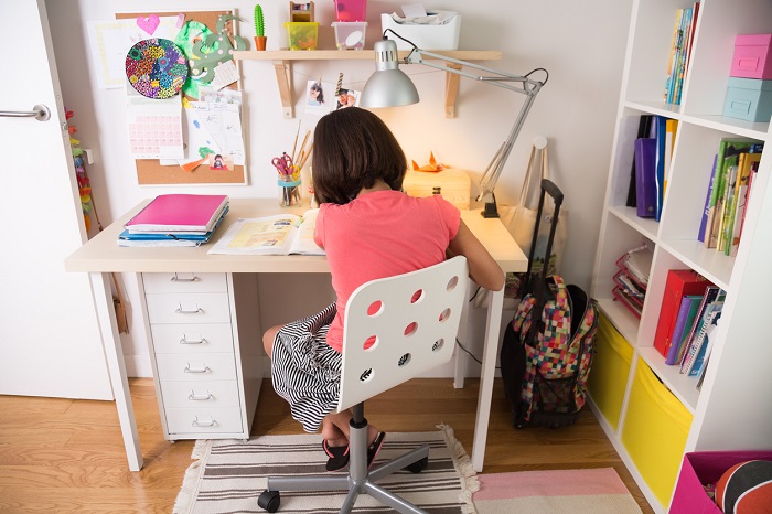 Little girl doing homework at home in her desk.