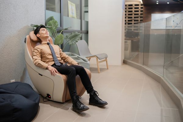 A young man in a tan suit relaxing in a massage chair 