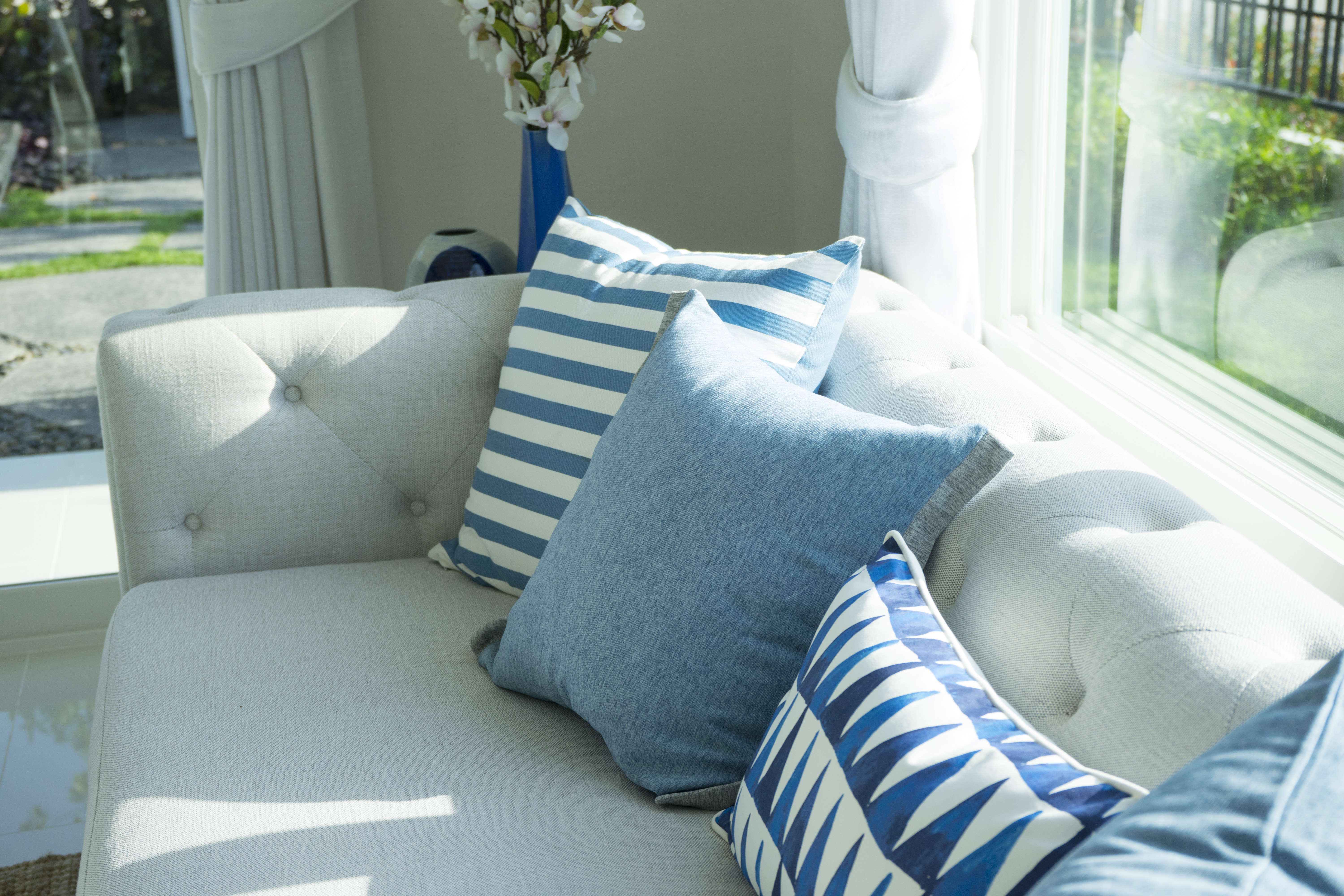 A white tufted sofa with blue and white accent pillows 