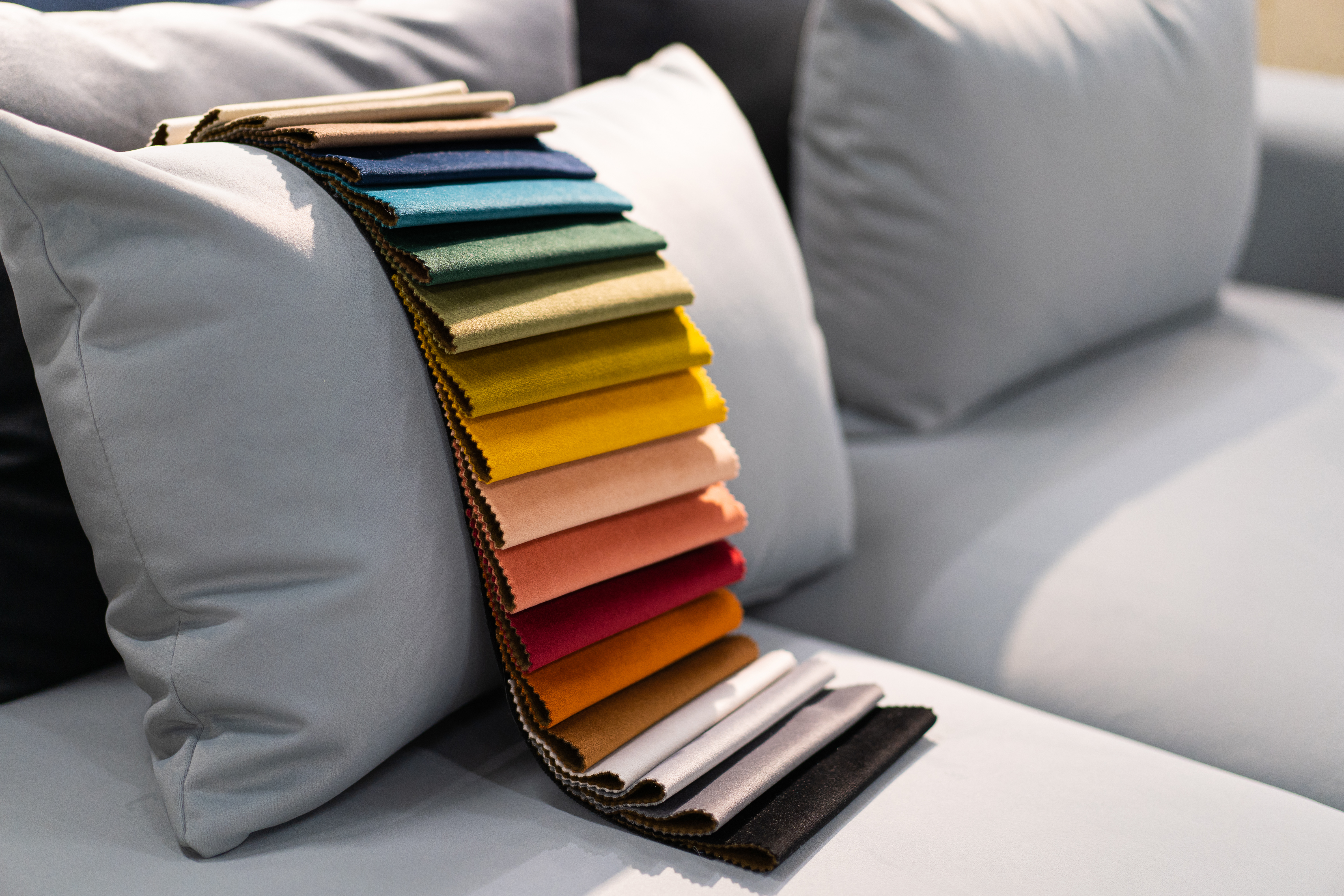 A grey sofa with colorful fabric samples 