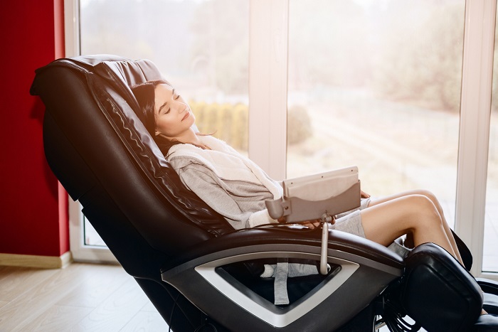Young woman relaxing on the massaging chair at home. 