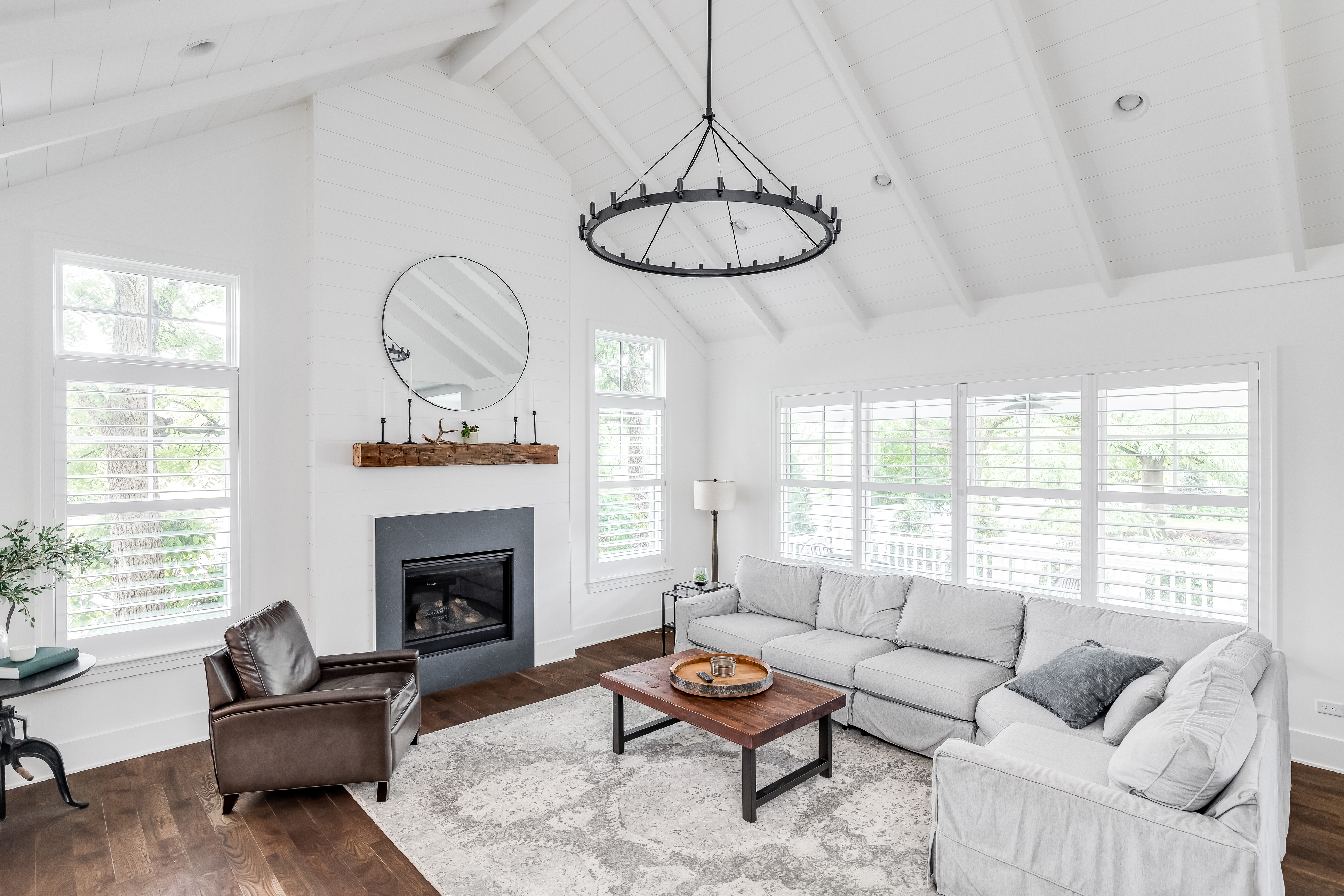 A modern farmhouse den with white furniture and wood and dark wood elements 