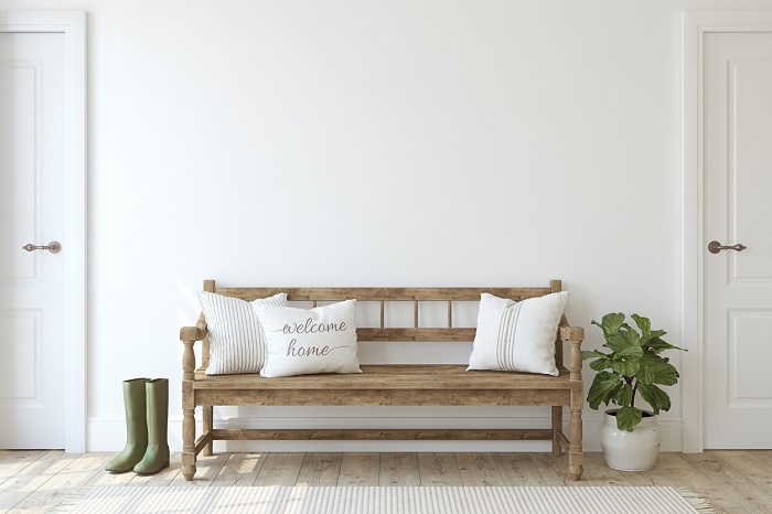 Farmhouse entryway with wooden bench near white wall.
