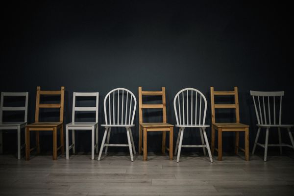 A variety of dining chairs against a black wall 