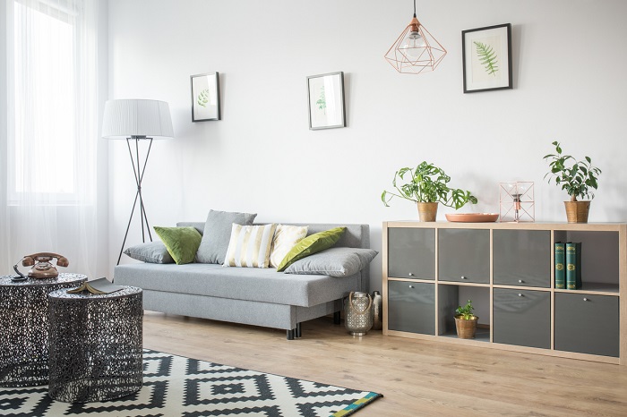Living room with openwork metal table, grey sofa, and bookcase.