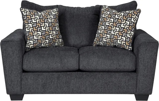 Stock photo of a dark gray colored fabric loveseat with two uniquely patterned throw pillows. 