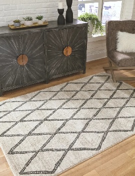 The Signature Design by Ashley Jarmo collection area rug with décor 