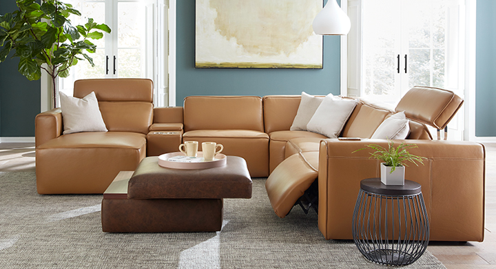 Modern living room with a large Palliser leather sectional and a leather ottoman in the middle. 