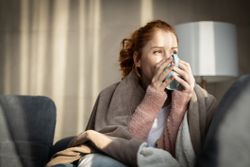  A smiling woman enjoying a hot beverage on a sofa