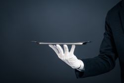  A servant in a black suit and white gloves holding a silver platter