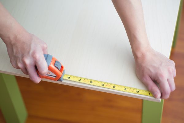 A person measuring a coffee table 
