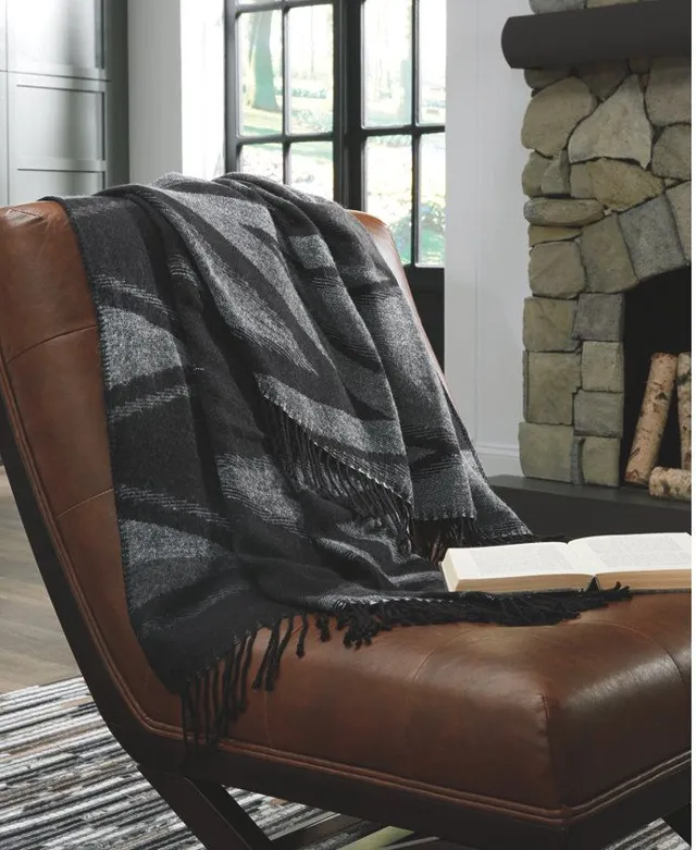 The Signature Design by Ashley Cecile throw blanket on a leather chair 