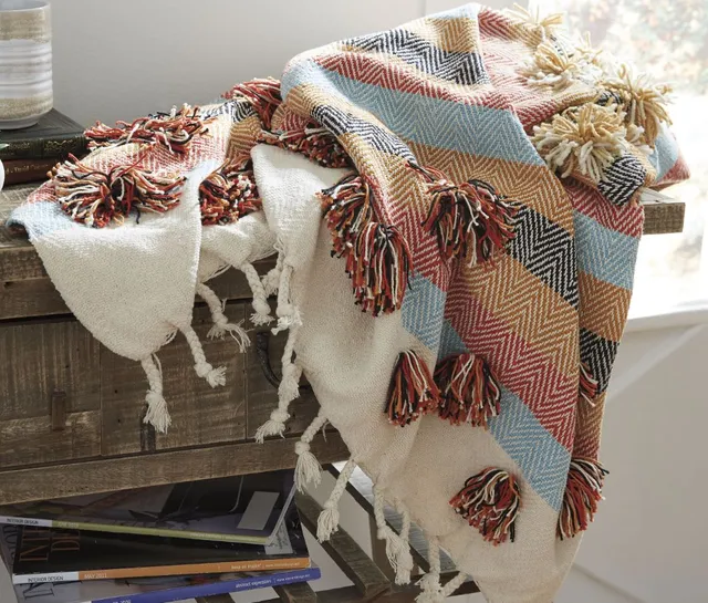 The Signature Design by Ashley Jacinta throw blanket casually draped on a desk 