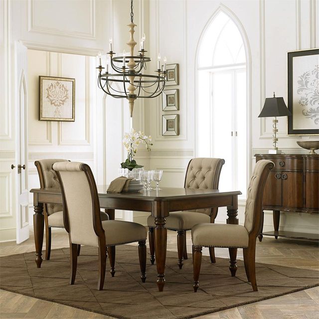 Traditoannly styled dining room with wooden table, upholstered chairs, and a metal chandelier hanging above.