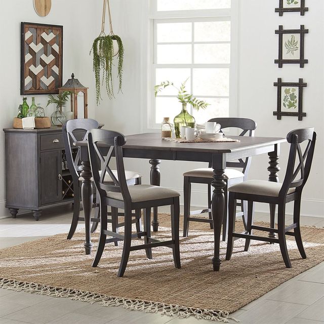 Modern dining area with square wooden table and four matching chairs sitting around with a hanging plant in the background.