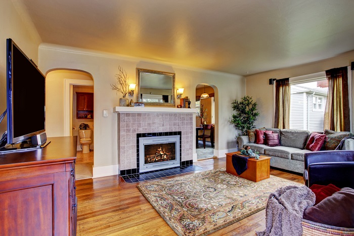 Traditional living room interior with sofa, tv, and view of fireplace.